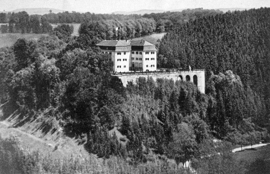 Panoramabild des Schlosses Grafeneck im Jahr 1930. Zu sehen ist das drei-flügelige Schloss auf einer Anhöhe, umgeben von Wald.