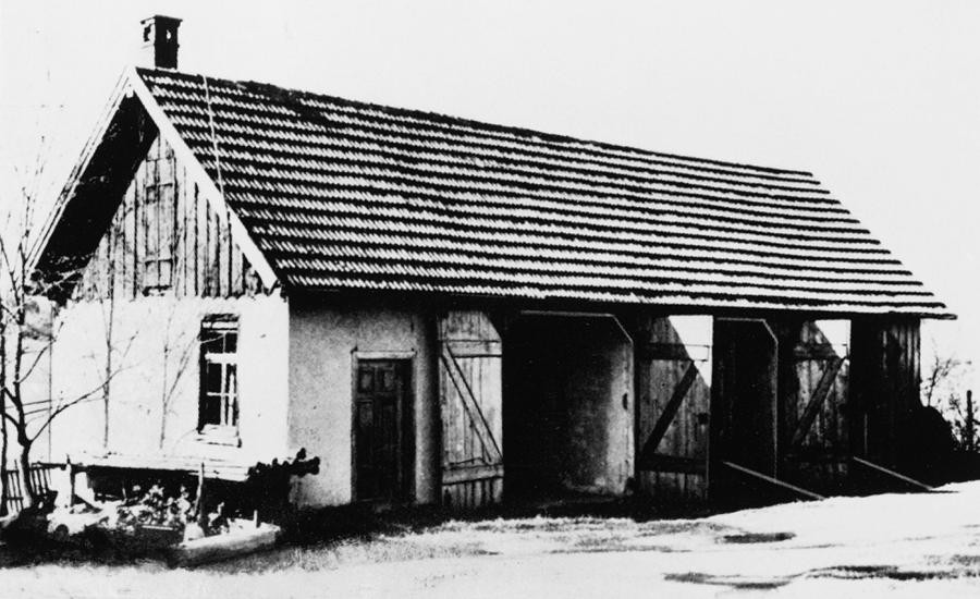 Zur Landwirtschaft gehörendes Gebäude ("Remise"), in das zur Jahreswende 1939/40 eine Gaskammer eingebaut wurde. Das Bild zeigt ein längliches, weißes Gebäude. Links am Gebäude befindet sich eine Tür, rechts daneben drei Tore aus Holz. Die beiden mittleren Tore sind geöffnet.